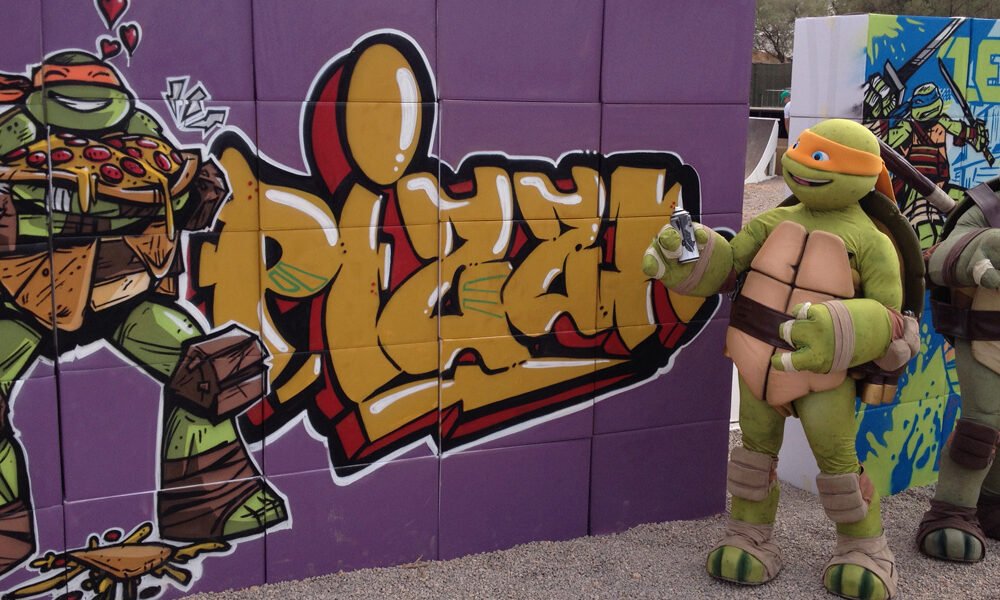 Tortugas-ninja-con-graffiti-en-evento Tortuga Ninja junto a graffiti en evento.