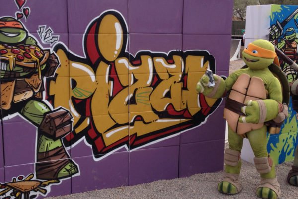 Tortugas-ninja-con-graffiti-en-evento Tortuga Ninja junto a graffiti en evento.
